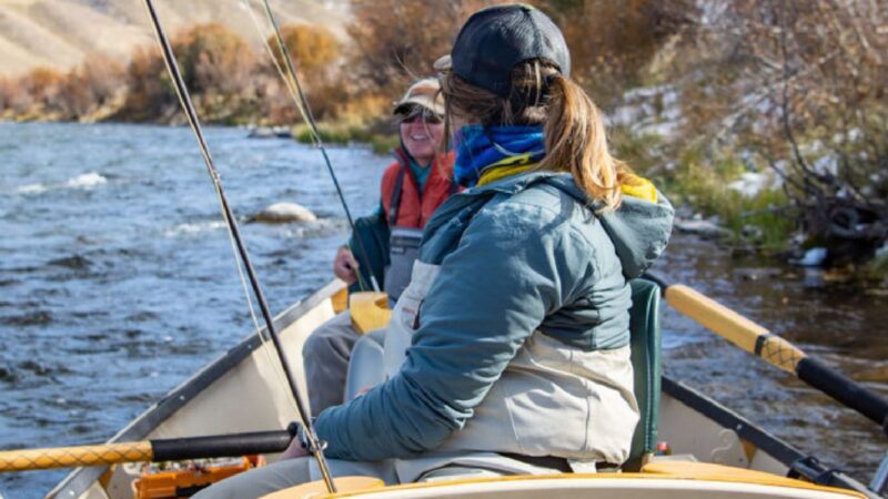 Two women sit in a boat speaking to one another as they foat down a river during a trip with The Tackle Shop.