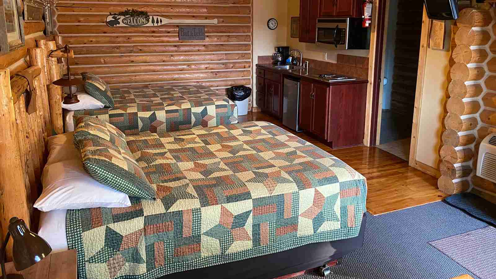 Interior of a cabin at the Lure Me Inn in Ennis, Montana with two queen beds and a kitchenette.