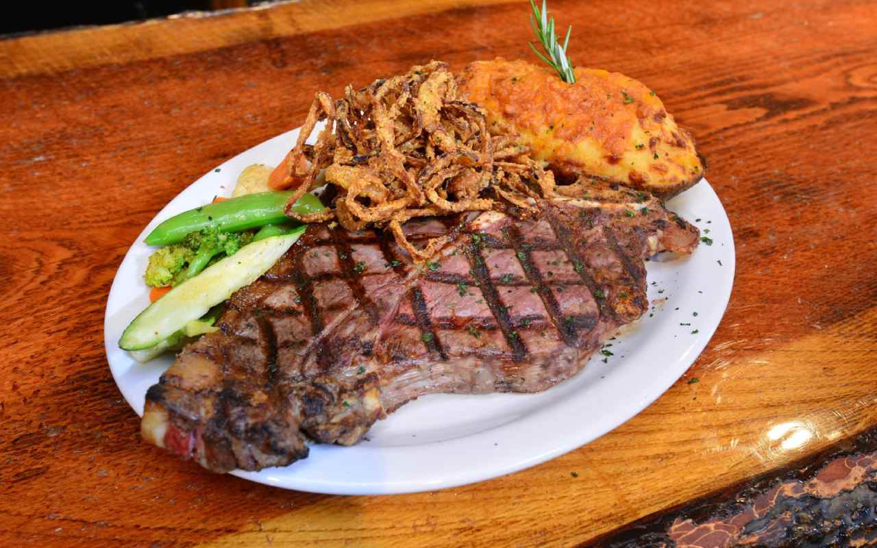 12-ounce ribeye steak with a side of vegetables and a baked potato from McAllister Steakhouse and Bar in Ennis, MT.