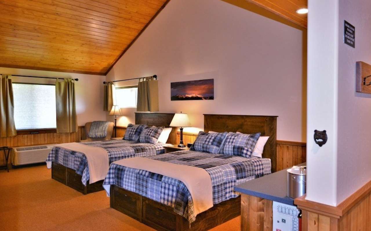 Interior of a room at the McAllister Inn in Ennis, Montana with two queen beds and wood plank vaulted ceilings.