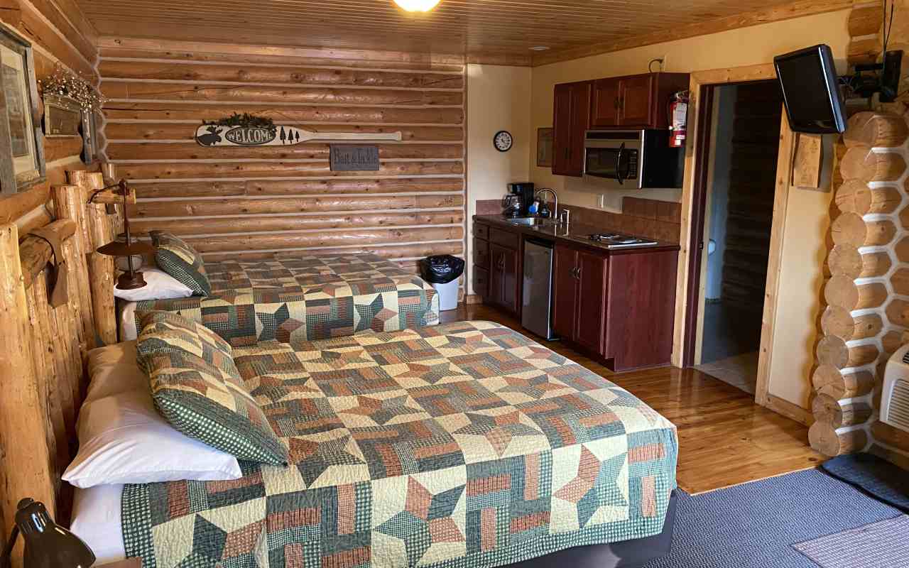 Interior of a cabin at the Lure Me Inn in Ennis, Montana with two queen beds and a kitchenette.